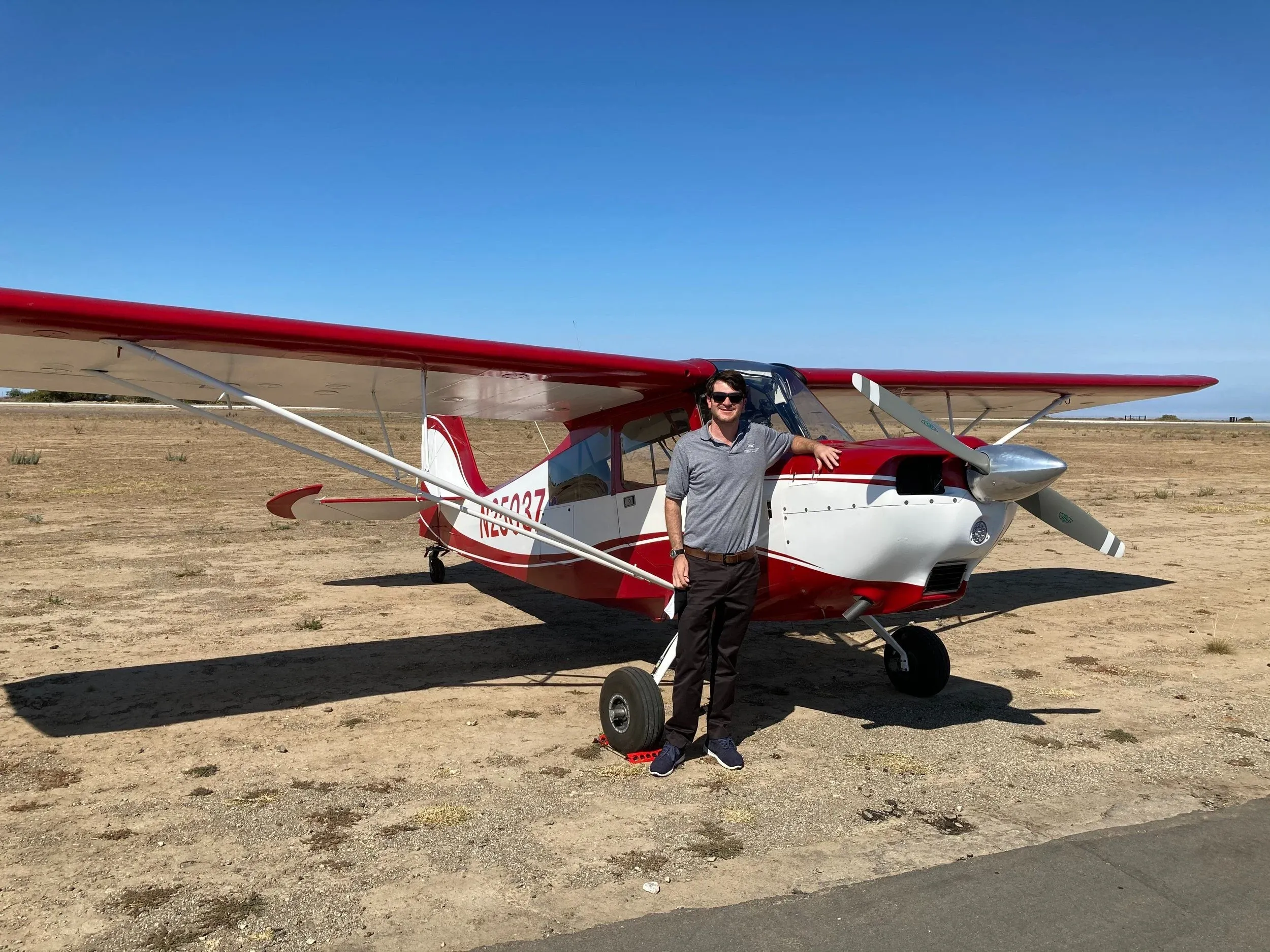 Founder standing by red and white taildragger aircraft